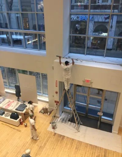 AW Painting General Contractors, Inc. painters working at GAP store. Two workers watching while one worker is on a ladder painting.